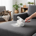PawLunor Lint Roller being used on dark sofa with cat nearby